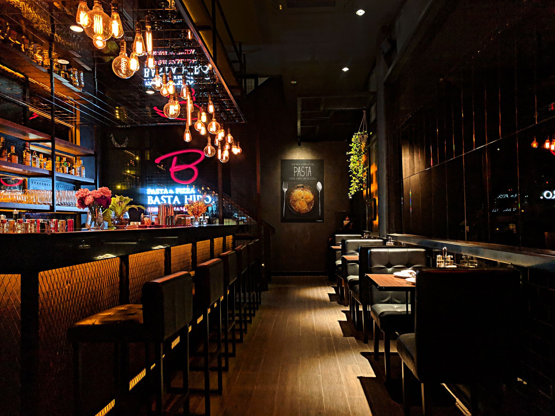 Bar de restaurant sombre avec ampoules suspendues, étagères éclairées et assises hautes.